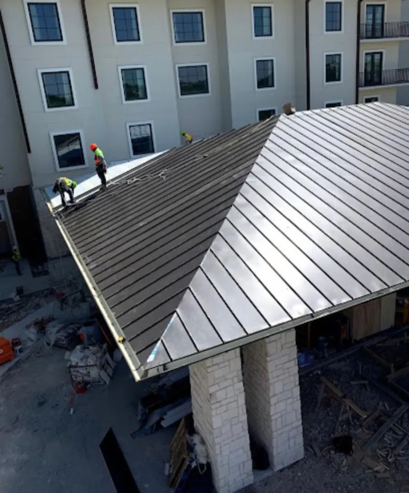 Crew installing standing seam metal roof panels on a commercial project in Minden